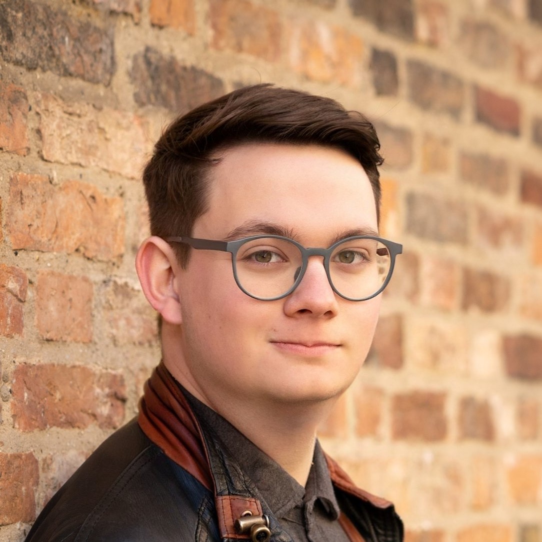 Alex Keen leaning against a brick wall.